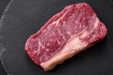 Fresh raw beef striploin steak with salt, spices and herbs