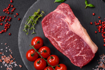 Fresh raw beef striploin steak with salt, spices and herbs
