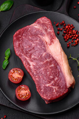 Fresh raw beef striploin steak with salt, spices and herbs