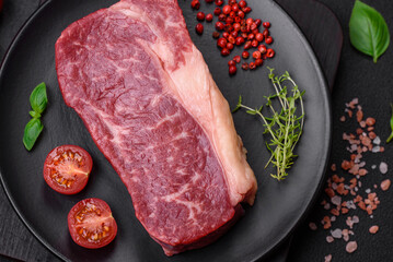 Fresh raw beef striploin steak with salt, spices and herbs