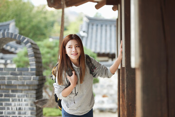 A young woman, a college student, traveling in a traditional Korean village with a backpack