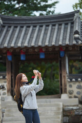 Fototapeta premium A young woman wearing a camera and taking pictures while traveling to tourist attractions with traditional Korean houses