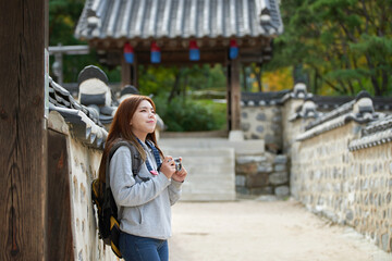 A young woman wearing a camera and taking pictures while traveling to tourist attractions with...
