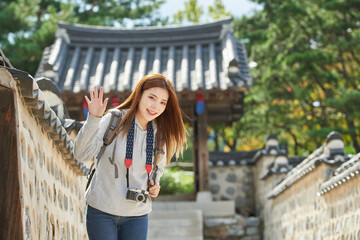 Fototapeta premium A young woman wearing a camera and taking pictures while traveling to tourist attractions with traditional Korean houses