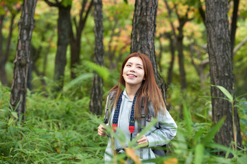 A young woman walking around in the woods taking pictures with a camera and backpack