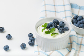 Yogurt with blueberries and fresh mint in white bowl for breakfast on  table napkin on white background