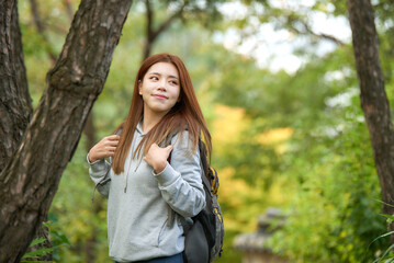 a young female college student traveling through the woods with a backpack