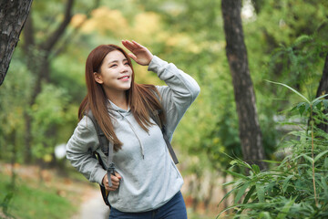 a young female college student traveling through the woods with a backpack