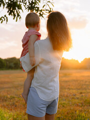 Mother with he daughter outdoor with sunset in park. Lifestyle family concept