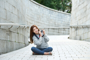 a young woman sitting in the street taking pictures with a camera while traveling