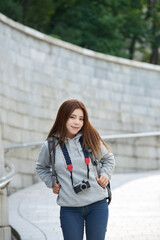 Fototapeta premium young woman who is taking pictures while traveling in Korea with a camera backpack