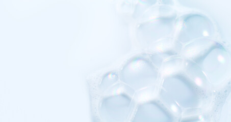 Foam border design on blue background. Liquid soap bubbles, Foam bubbles background. Soap foam popping bubble, white backdrop. Soap sud macro structure. Soap foam close-up. Clean, cleaning, washing.