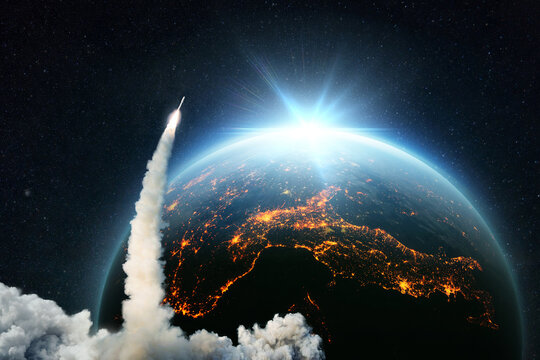 Space Rocket lift off. Space shuttle with smoke and blast takes off into space on a background of blue planet earth with amazing sunset. Successful start of a space mission. Travel to Earth.