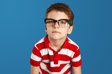 Closeup portrait of young tired, overwhelmed nerdy boy, stressed, isolated over blue background