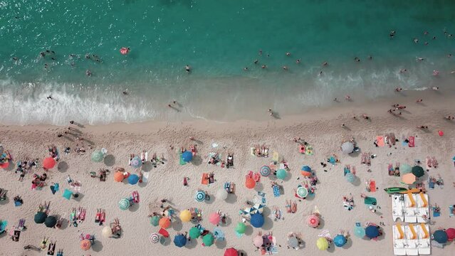 Footage 4k 25Fps: aerial view from the drone of the beach of Tropea in Calabria with the crystalline Caribbean sea, the bathers and the colored umbrellas. The video conveys a sense of peace and sereni
