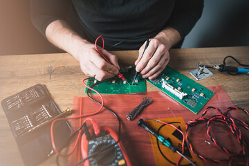 A man is checking the circuit of an electronic board with a multimeter. Fixing broken electonics.