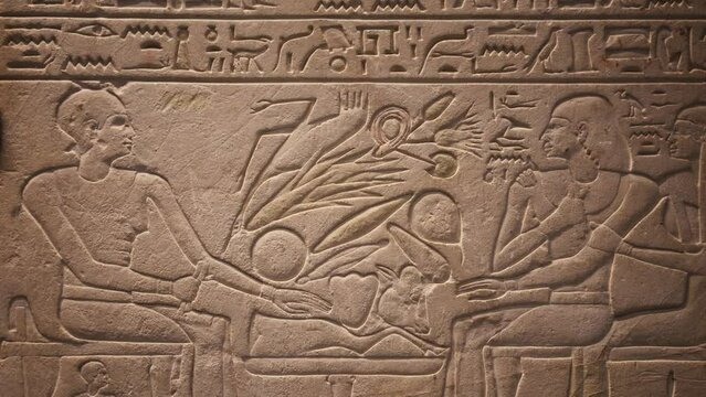 Ancient Egyptian Hieroglyphs and Carvings Depicting People Sitting at a Table With Food