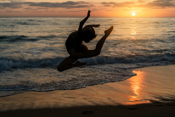 Silueta de chica realizando movimientos de gimnasia y baile al atardecer en playa paradisiaca