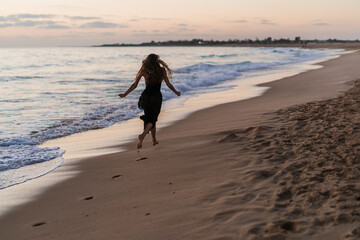 Figura de mujer a orilla del mar al atardecer