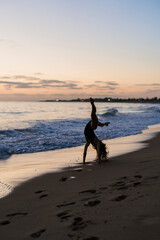 Fototapeta na wymiar Silueta de chica realizando movimientos de gimnasia y baile al atardecer en playa paradisiaca