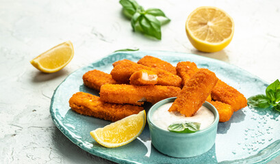 Crumbed fish sticks served with lemon and tartar sauce. Long banner format. top view