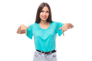 portrait of a pretty young caucasian brunette woman with long hair in a blue t-shirt showing with her hands at an advertising offer on a white background with copy space