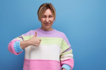 pleasant blond young woman in a striped sweater shows class on a blue background