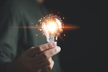 A man holds a bright light bulb, symbolizing creative new ideas, innovation, and inspiration. The concept of solution-oriented thinking and innovative technology is showcased in this creative moment.