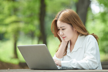 A young woman using a laptop in the park, a college student