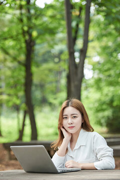 A young woman using a laptop in the park, a college student