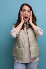 surprised brunette young lady in casual outfit on studio background