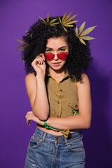 Beautiful rastafarian woman in red sunglasses with marijuana leaves in her hair. Legalization of...