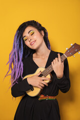 Beautiful rasta woman with purple and blue hair playing ukulele. Lady musician with dreadlocks....