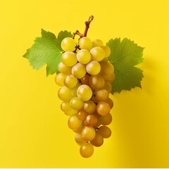 Bunch of white grapes with green leaves on a yellow background.