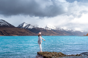 Asian female model enjoy the beautiful scenic sunrise view of Lake Pukaki east bank, with their mesmerizing turquoise hue and reflect the majestic snow-capped Southern Alps.