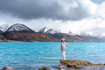 Asian female model enjoy the beautiful scenic sunrise view of Lake Pukaki east bank, with their mesmerizing turquoise hue and reflect the majestic snow-capped Southern Alps.