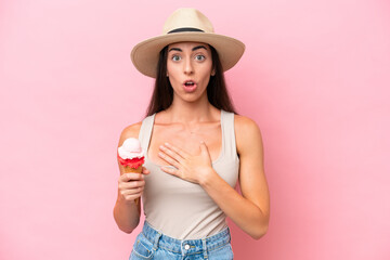 Young caucasian woman with a cornet ice cream isolated on pink background surprised and shocked...