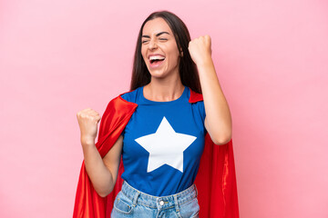 Super Hero Caucasian woman isolated on pink background celebrating a victory