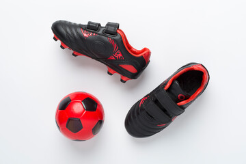 Football shoes with ball on color background, top view
