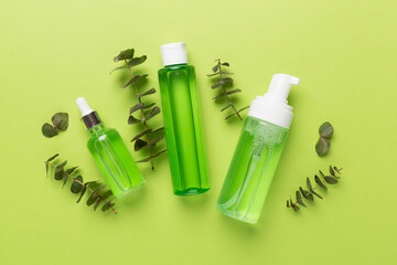 Herbal face care products on color background, top view