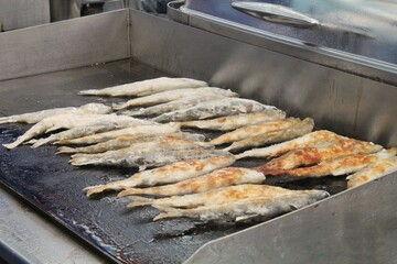 Preparing fish on a flat grill with oil. Outdoor seafood barbecue cooking. Picnic on backyard at open air. Street food festival. Pescetarian diet. Healthy ingredients