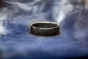 Rune ring covered in smoke on a dark background