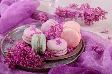 Sweet pastel french macaroons and lilac flowers on light gray background. Beautiful composition for bakery and pastry shop