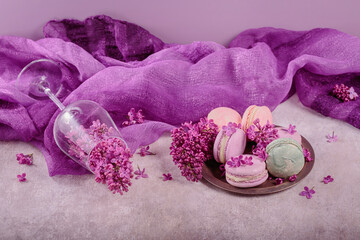 Sweet pastel french macaroons and lilac flowers on light gray background. Beautiful composition for bakery and pastry shop