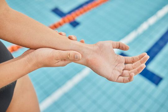 Hand, wrist pain and a swimmer by a pool in the gym closeup after emergency or accident during training. Fitness, water and a swimming athlete with an injury, arthritis or tendinitis in her arm