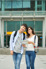 A couple waiting for a train at a Korean train station while looking at a travel map