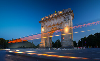 Arch of Triumph in Bucharest, travel to Romania. Long exposure photo with traffic lights in the morning blue hour sky. Beautiful landscape photo of Bucharest.