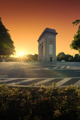 Fototapeta premium Sunrise in Bucharest. Wide photo during a spectacular summer sunrise with the silhouette of Arch of Triumph landmark in Bucharest. Travel to Romania.