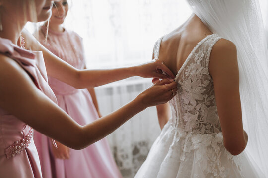 the bride, with her girlfriends in matching pink dresses, in the morning, help the bride get ready for the wedding ceremony