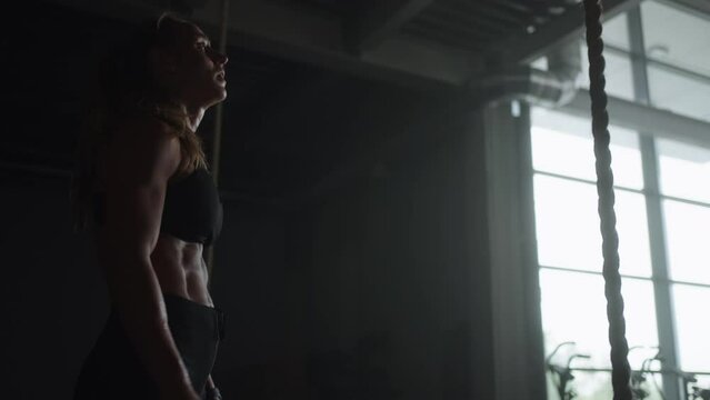 Strong Sportswoman Climbing Rope In Gym, Training Alone, Developing Endurance And Strength